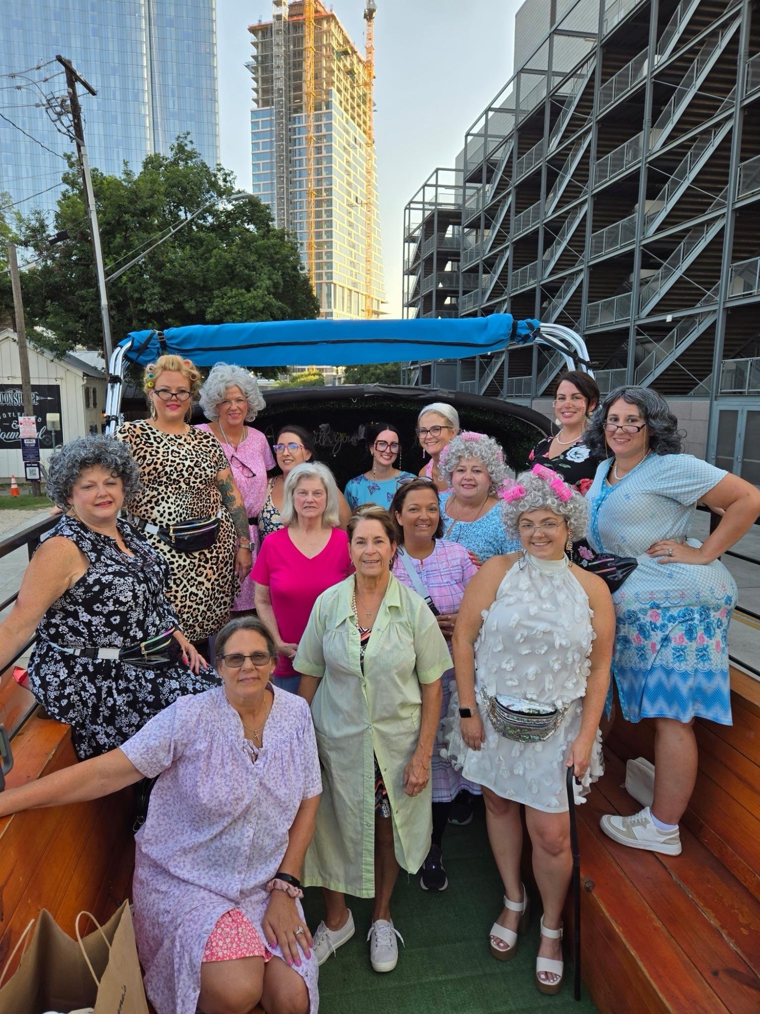 A group of people dressed eccentrically on a wooden platform, with buildings in the background.